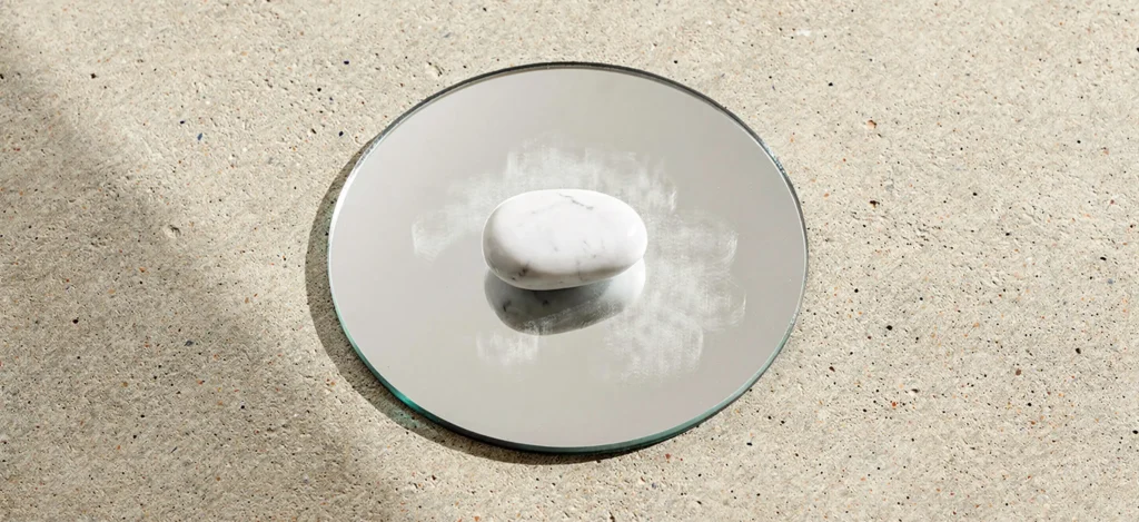 identité visuelle marque engagée — galet de marbre blanc sur miroir circulaire