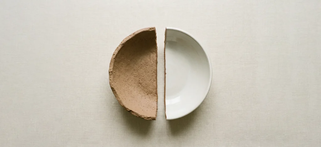 deux demi assiettes en terre et en céramique sur une nappe beige en lin